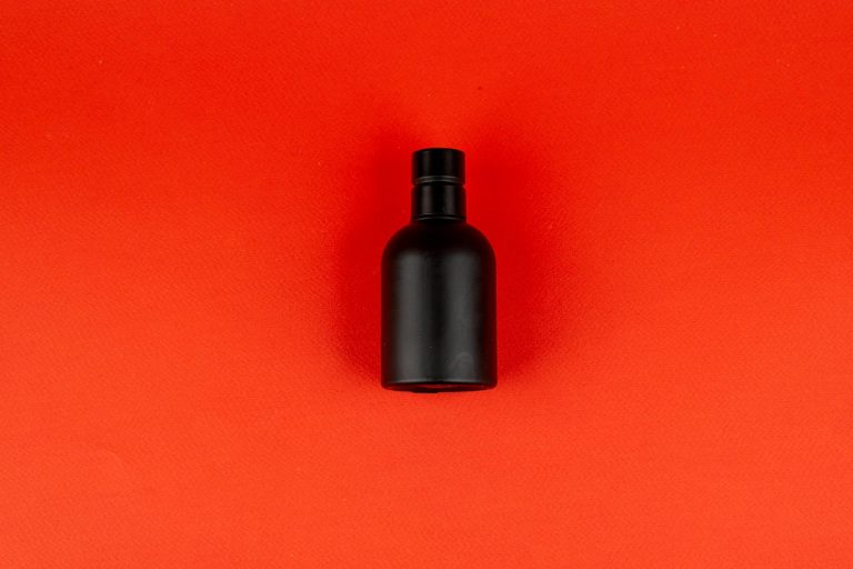 Armaf Club De Nuit Intense Man - elegancka czarna flasza perfum na czerwonym tle